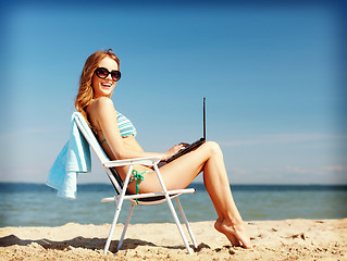 Image showing girl looking at tablet pc on the beach