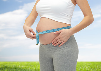 Image showing close up of pregnant woman measuring her tummy