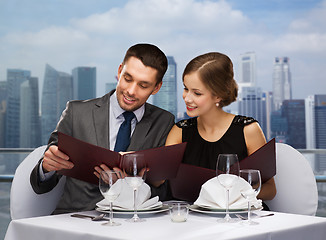 Image showing smiling couple with menus at restaurant