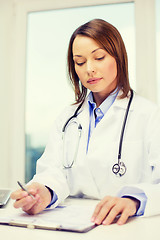 Image showing busy doctor with laptop computer and clipboard