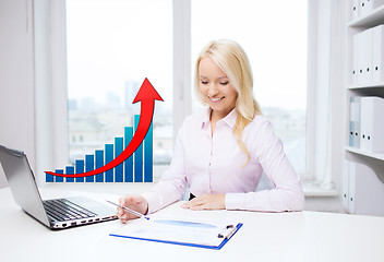 Image showing smiling businesswoman with laptop and papers