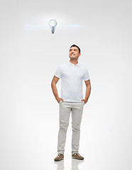 Image showing smiling man looking up to lighting bulb