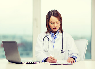 Image showing busy doctor with laptop computer and clipboard