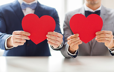 Image showing close up of male gay couple holding red hearts