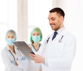 Image showing smiling male doctor with clipboard and stethoscope