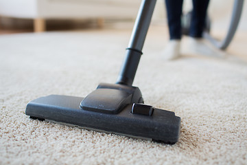 Image showing close up of woman legs with vacuum cleaner at home