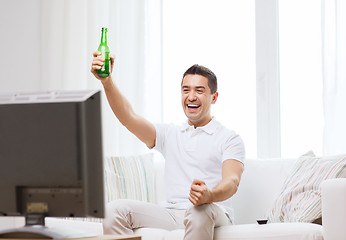 Image showing smiling man watching tv and drinking beer at home