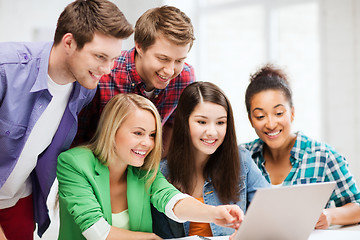 Image showing smiling students looking at laptop at school