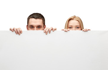 Image showing happy couple hiding behind big white blank board