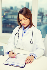 Image showing busy doctor with laptop computer and clipboard