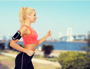 Image showing sporty woman running with smartphone and earphones