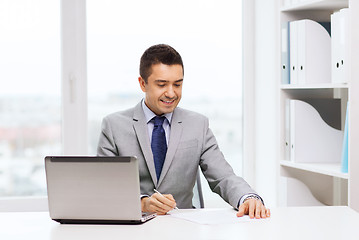 Image showing smiling businessman with laptop and papers