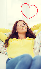 Image showing smiling young woman lying on sofa at home