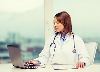 Image showing busy doctor with laptop computer and clipboard