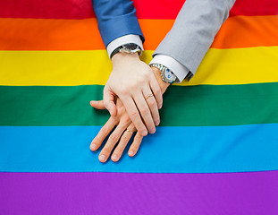 Image showing close up of male gay couple hands on rainbow flag