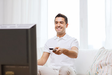 Image showing smiling man with remote control watching tv