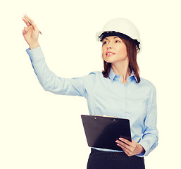 Image showing smiling businesswoman in helmet with clipboard