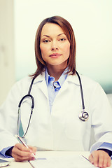 Image showing busy doctor with laptop computer and clipboard