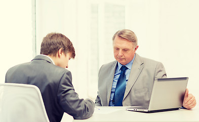 Image showing older man and young man signing papers in office