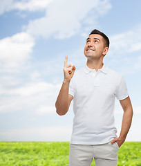 Image showing smiling man in white t-shirt pointing finger up