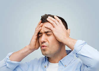 Image showing unhappy man with closed eyes touching his forehead