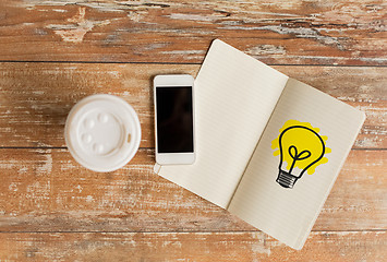 Image showing close up of notebook, coffee cup and smartphone