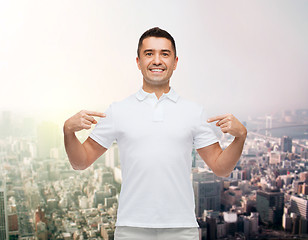 Image showing smiling man in t-shirt pointing fingers on himself