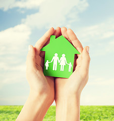 Image showing hands holding green house with family