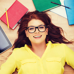 Image showing smiling student in eyeglasses lying on floor