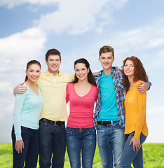 Image showing group of smiling teenagers over blue sky and grass