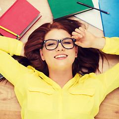 Image showing smiling student in eyeglasses lying on floor