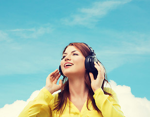 Image showing smiling young girl in headphones at home