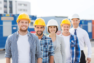 Image showing group of smiling builders in hardhats outdoors