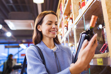 Image showing happy woman choosing and buying wine in market