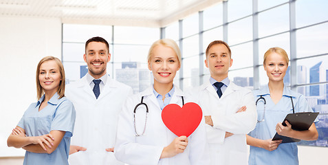 Image showing happy young doctors cardiologists with red heart