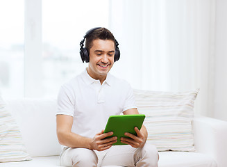 Image showing smiling man with tablet pc and headphones at home