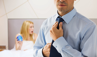 Image showing close up of man adjusting tie on neck in bedroom