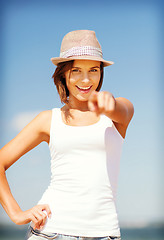 Image showing girl in hat pointing at you on the beach