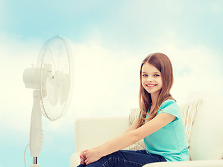 Image showing smiling little girl with big fan at home