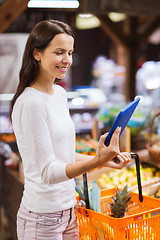 Image showing happy woman with basket and tablet pc in market