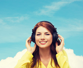 Image showing smiling young girl in headphones at home