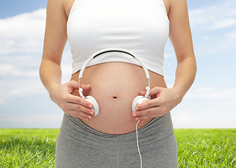 Image showing close up of pregnant woman and headphones on tummy