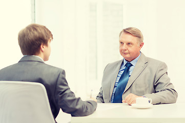 Image showing older man and young man signing papers in office