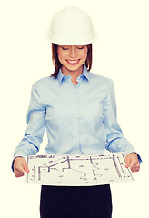 Image showing businesswoman in helmet looking at blueprint