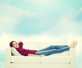 Image showing smiling teenage girl lying on sofa