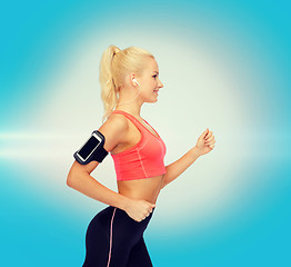 Image showing sporty woman running with smartphone and earphones