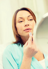 Image showing woman applying lipstick and holding mirror