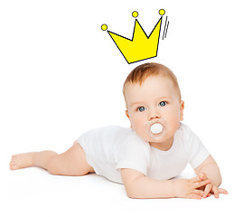 Image showing smiling baby lying on floor with dummy in mouth