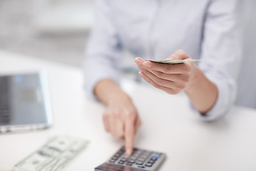 Image showing close up of woman counting money with calculator