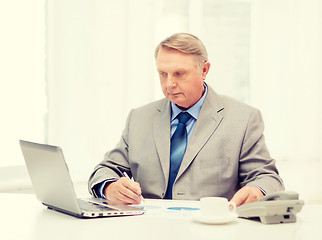 Image showing busy older businessman with laptop and telephone